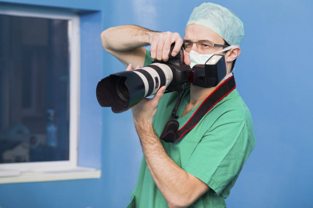 Young doctor photographing the medical procedures during surgery.